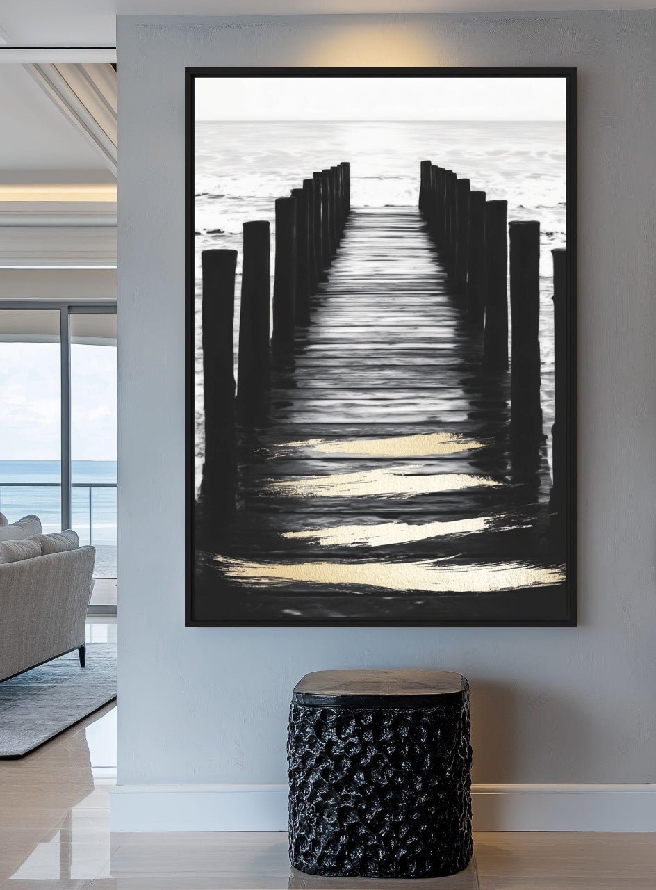 Monochrome ocean pier artwork on a pale gray wall above a black textured stool