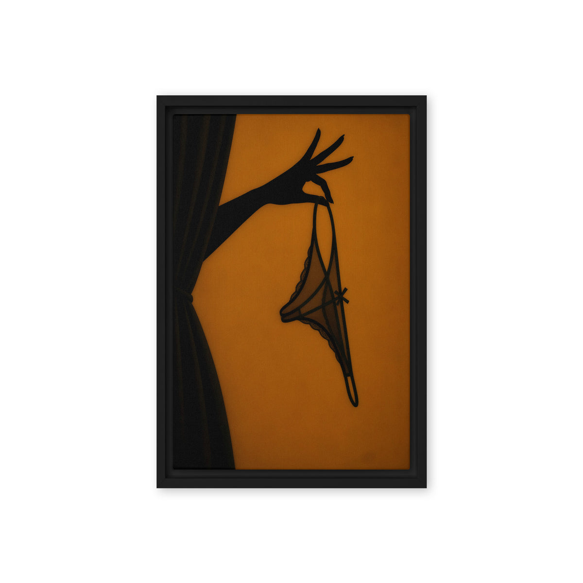 A black silhouette of a hand holds delicate lingerie against an amber-orange background; front view in a black frame, 12 x 18 in canvas