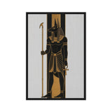 Black and gold Anubis figure holding a staff against pale vertical panels, front view with black frame, 24″×36″ nominal canvas