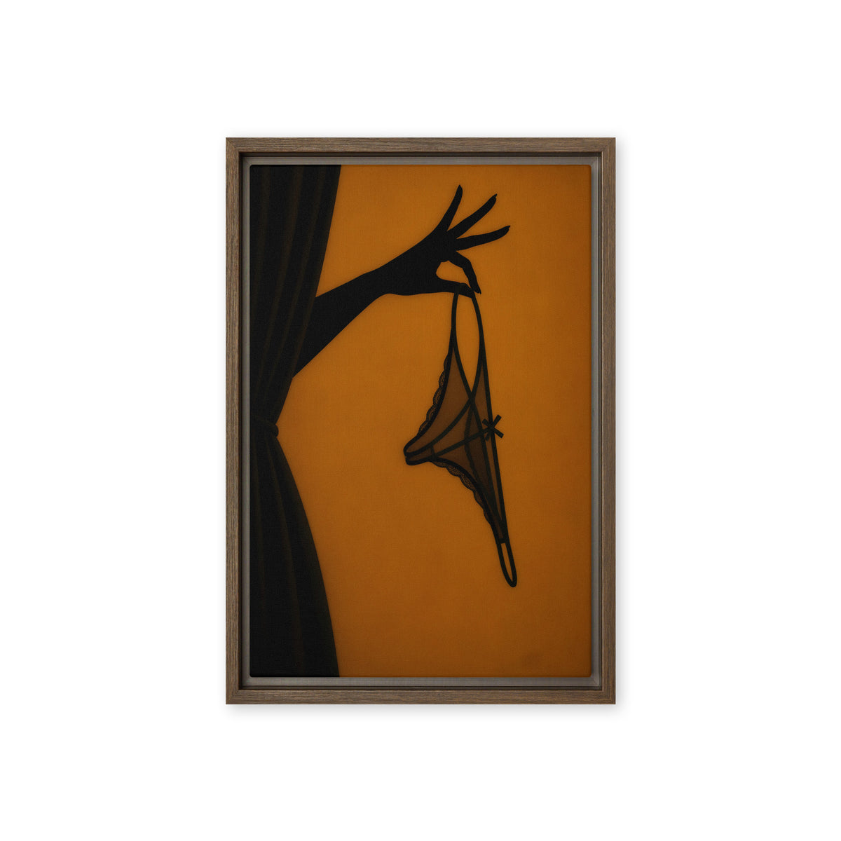 A black silhouette of a hand holds delicate lingerie against an amber-orange background; front view in a brown frame, 12 x 18 in canvas